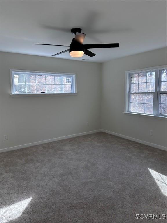 carpeted spare room featuring plenty of natural light and ceiling fan