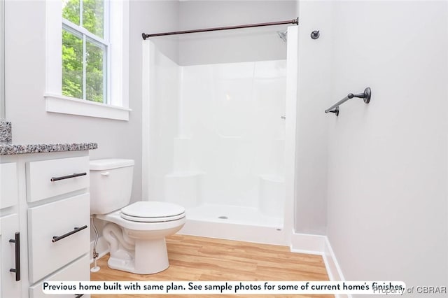 bathroom with toilet, vanity, walk in shower, and wood finished floors