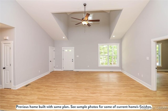 unfurnished living room featuring plenty of natural light, ceiling fan, high vaulted ceiling, and light hardwood / wood-style flooring