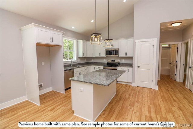 kitchen featuring appliances with stainless steel finishes, sink, pendant lighting, white cabinets, and a kitchen island