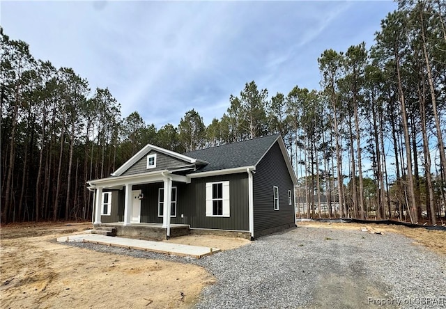 view of front of home with a porch, a shingled roof, and driveway