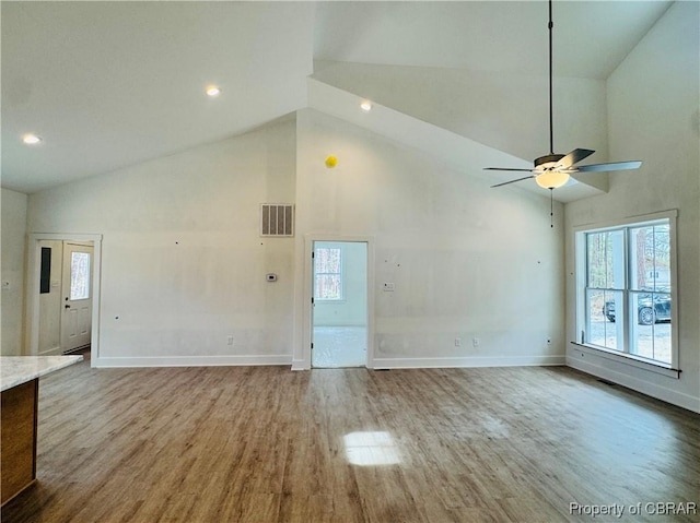 unfurnished living room featuring visible vents, wood finished floors, baseboards, and high vaulted ceiling