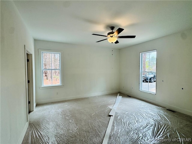 unfurnished bedroom with visible vents, multiple windows, a ceiling fan, and baseboards