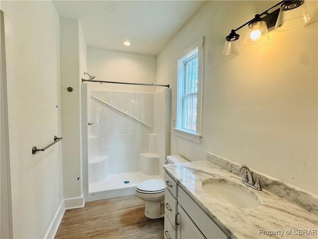 bathroom featuring toilet, vanity, walk in shower, and wood finished floors