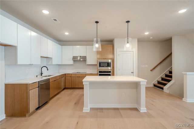 kitchen featuring white cabinets, sink, light hardwood / wood-style floors, appliances with stainless steel finishes, and a kitchen island