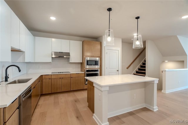 kitchen with sink, light hardwood / wood-style flooring, decorative light fixtures, white cabinetry, and stainless steel appliances