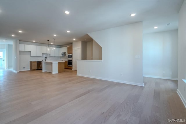 unfurnished living room featuring sink and light wood-type flooring