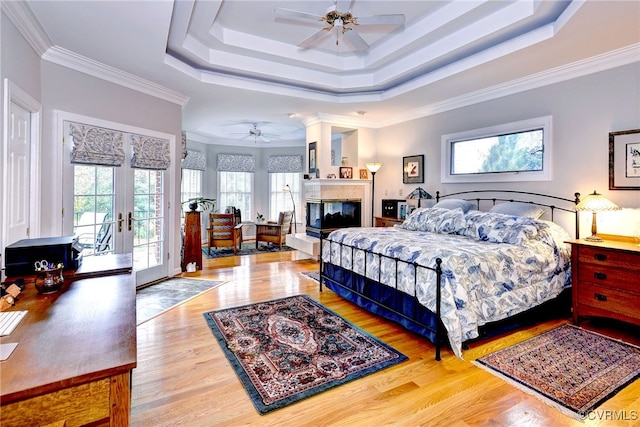 bedroom featuring access to exterior, french doors, ornamental molding, a raised ceiling, and ceiling fan