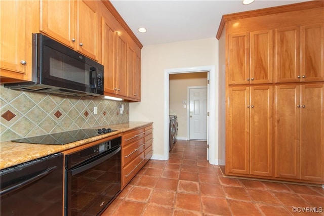 kitchen featuring black appliances, washing machine and dryer, light stone countertops, and tasteful backsplash