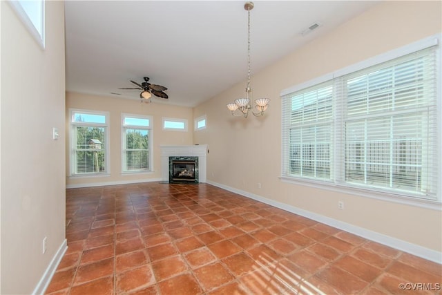 unfurnished living room featuring tile patterned flooring, ceiling fan with notable chandelier, and a healthy amount of sunlight