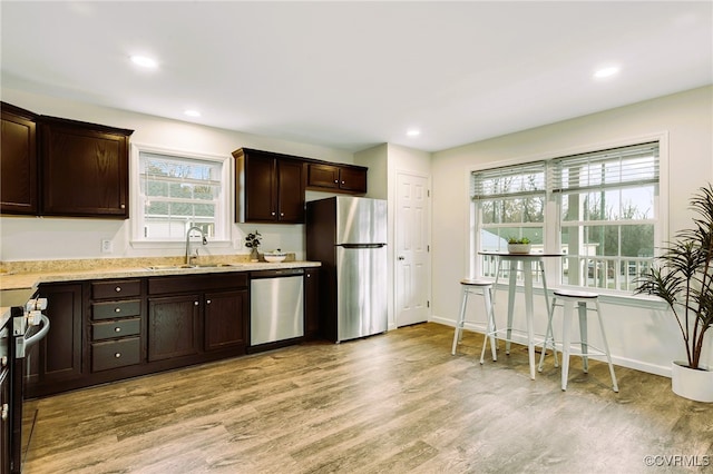 kitchen featuring appliances with stainless steel finishes, light wood-type flooring, dark brown cabinets, and sink