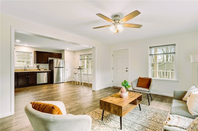 living room with ceiling fan, sink, and light hardwood / wood-style floors