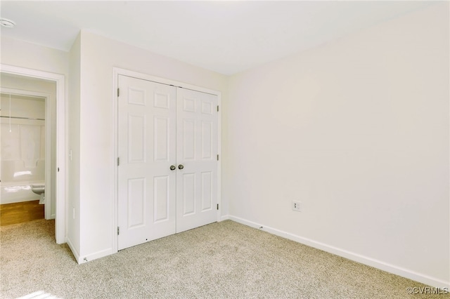 unfurnished bedroom with light colored carpet and a closet