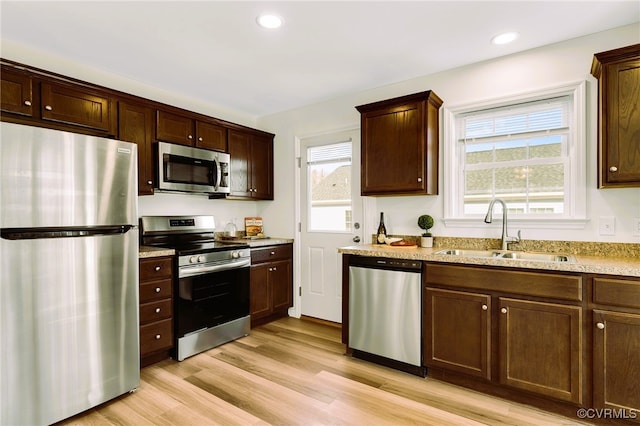 kitchen with appliances with stainless steel finishes, light hardwood / wood-style flooring, plenty of natural light, and sink