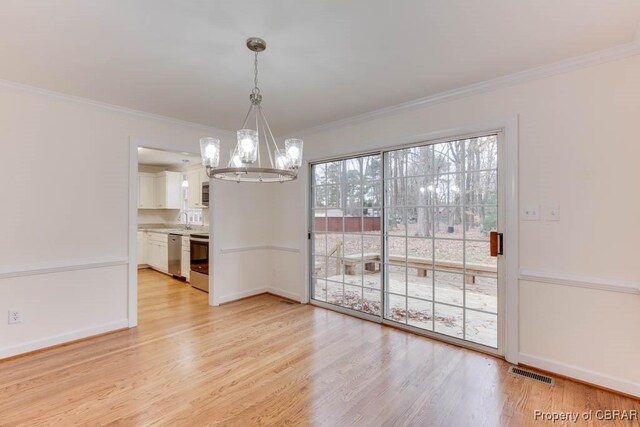 unfurnished dining area featuring ornamental molding, sink, a notable chandelier, and light hardwood / wood-style floors