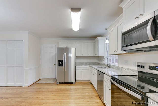 kitchen with sink, white cabinetry, crown molding, light hardwood / wood-style flooring, and stainless steel appliances