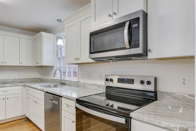 kitchen with stainless steel appliances, sink, pendant lighting, and white cabinets