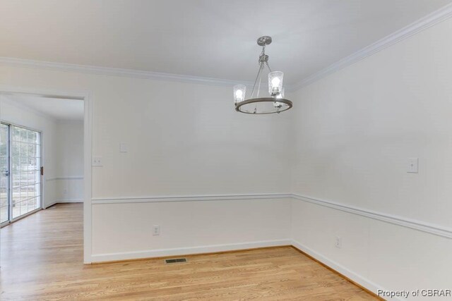 empty room with ornamental molding, an inviting chandelier, and light hardwood / wood-style floors