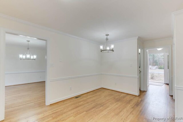 unfurnished room with hardwood / wood-style flooring, ornamental molding, and a notable chandelier