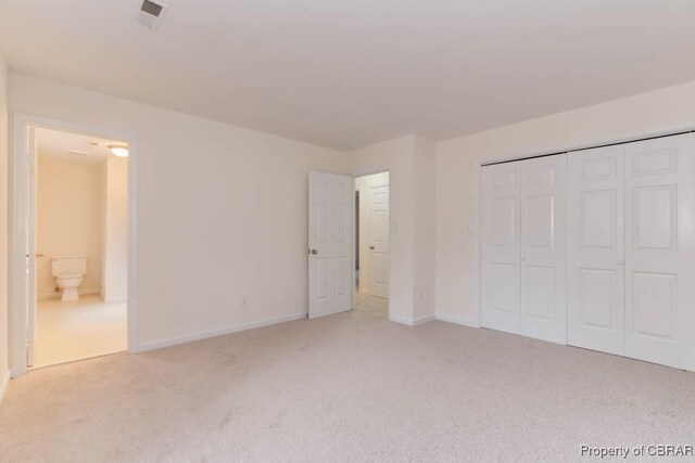 unfurnished bedroom with light colored carpet and a closet