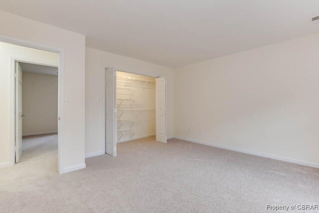 unfurnished bedroom featuring light colored carpet and a closet