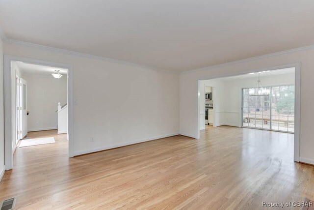 unfurnished living room with crown molding, a notable chandelier, and light hardwood / wood-style floors