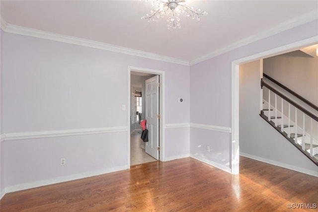 empty room with crown molding, hardwood / wood-style floors, and a chandelier