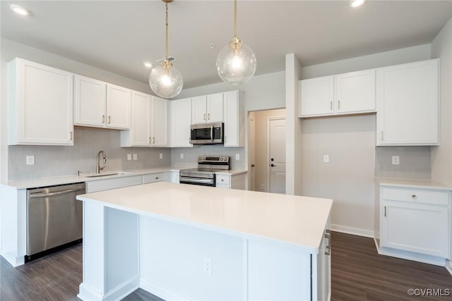 kitchen with stainless steel appliances, sink, pendant lighting, white cabinets, and a kitchen island