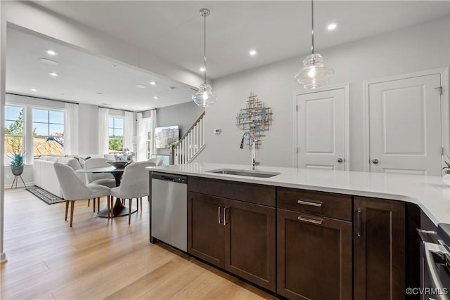 kitchen featuring stainless steel dishwasher, dark brown cabinets, sink, pendant lighting, and light hardwood / wood-style flooring