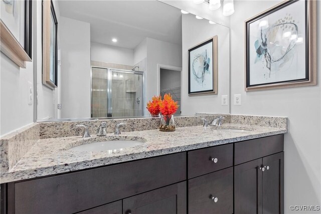 bathroom featuring a shower with door and vanity