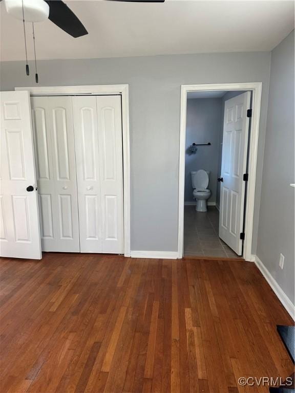 unfurnished bedroom featuring wood-type flooring, ensuite bath, a closet, and ceiling fan