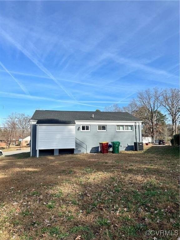 back of property featuring central AC unit and a yard