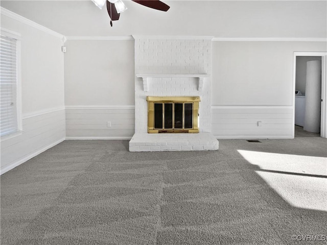 unfurnished living room with carpet floors, a brick fireplace, ceiling fan, and ornamental molding