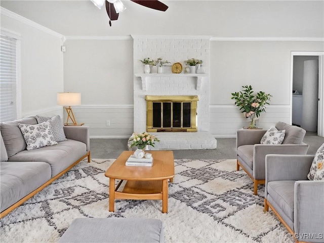 living room featuring carpet floors, a brick fireplace, ceiling fan, and crown molding