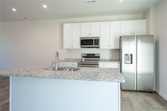 kitchen with sink, light hardwood / wood-style floors, a kitchen island with sink, white cabinets, and appliances with stainless steel finishes