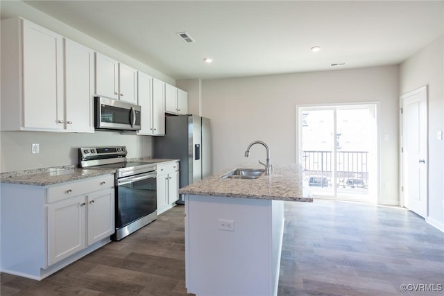 kitchen with appliances with stainless steel finishes, a kitchen island with sink, sink, white cabinets, and dark hardwood / wood-style floors