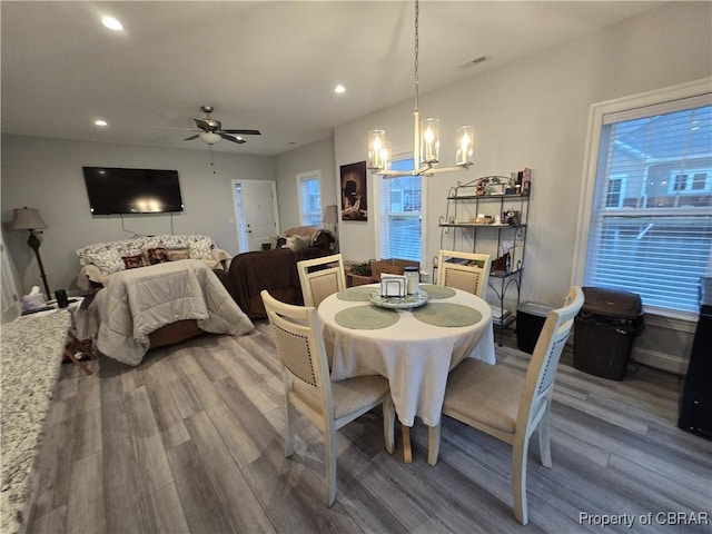 dining space with ceiling fan with notable chandelier and wood-type flooring