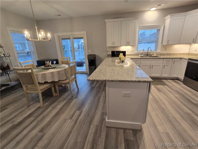 kitchen with sink, hanging light fixtures, decorative backsplash, white cabinetry, and wood-type flooring