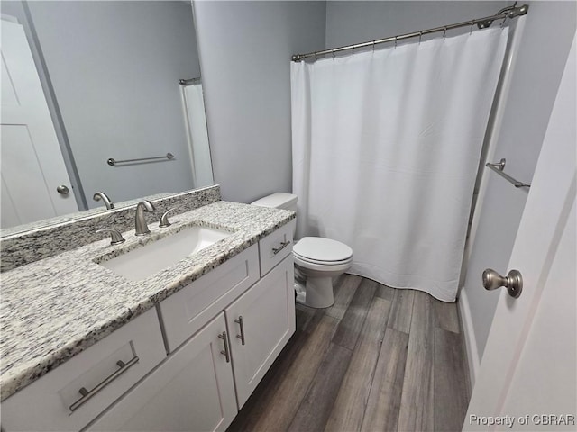 bathroom featuring curtained shower, vanity, wood-type flooring, and toilet