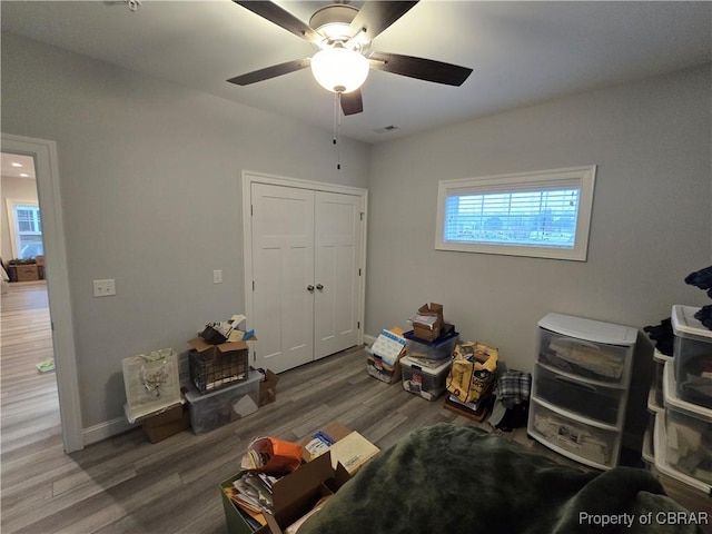 bedroom with a closet, visible vents, wood finished floors, baseboards, and ceiling fan