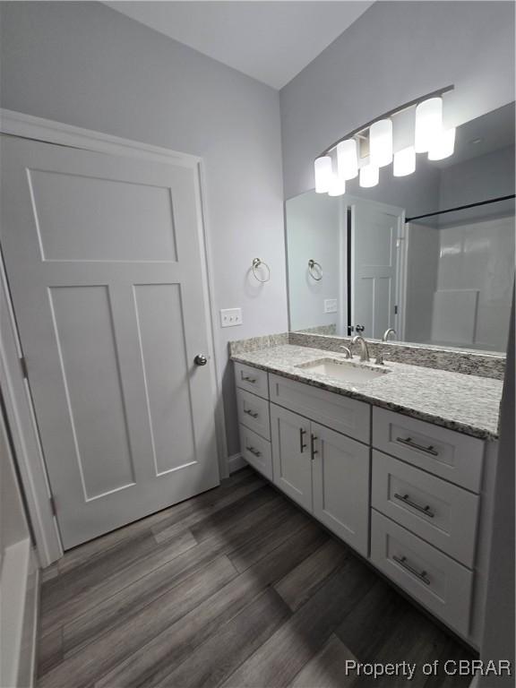 bathroom featuring hardwood / wood-style floors, vanity, and a shower