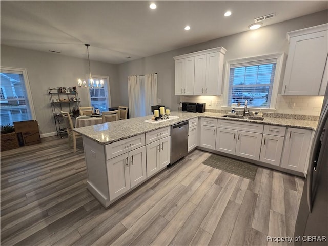 kitchen featuring sink, stainless steel dishwasher, hardwood / wood-style flooring, white cabinetry, and kitchen peninsula