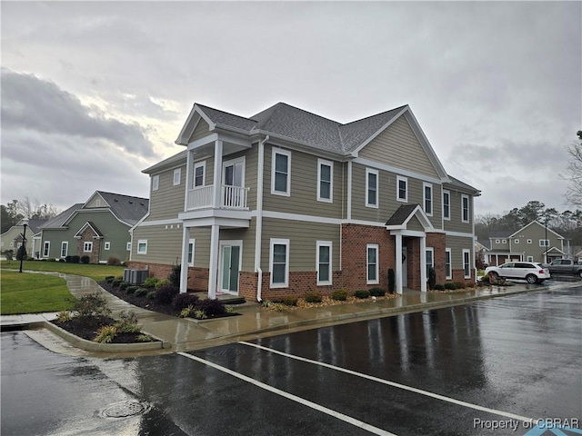 view of side of home with brick siding, central AC, a balcony, and a residential view