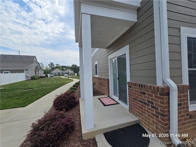 exterior space with a lawn, brick siding, fence, and a residential view