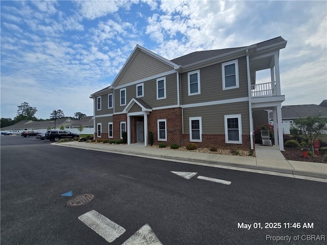 view of front of property with a balcony and brick siding