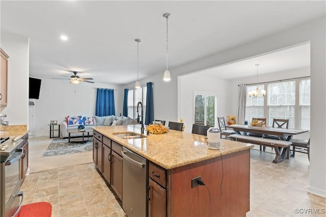 kitchen with a kitchen island with sink, ceiling fan with notable chandelier, hanging light fixtures, sink, and appliances with stainless steel finishes