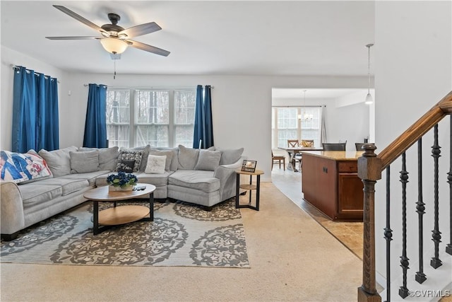 carpeted living room featuring ceiling fan with notable chandelier