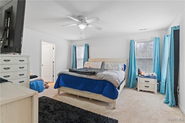 bedroom with multiple windows, light colored carpet, and ceiling fan