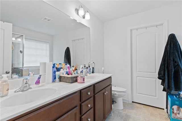 bathroom featuring vanity, a shower with shower door, and toilet