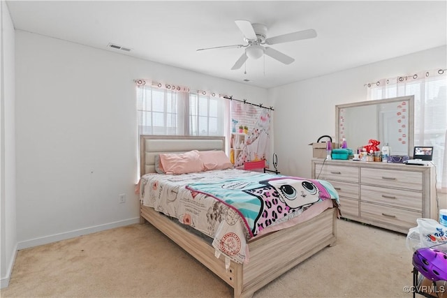 bedroom with ceiling fan, light carpet, and multiple windows